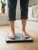 Adult standing on a digital bathroom scale at home