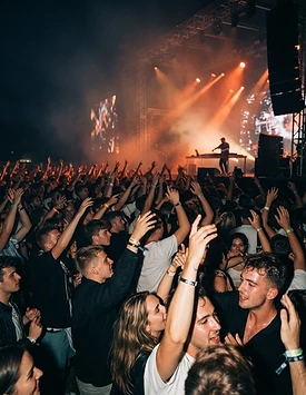 Público de show dançando sob luzes alaranjadas