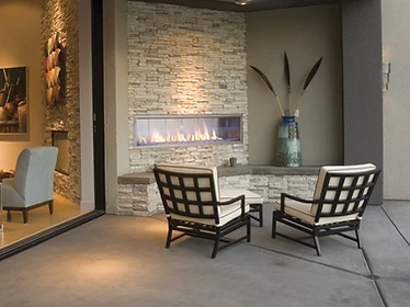 Firegear Kalea Bay outdoor linear fireplace with stacked stone wall at twilight