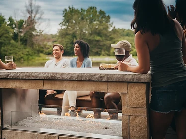 Empire Carol Rose 48ST stone fireplace with people gathered around socializing outdoors
