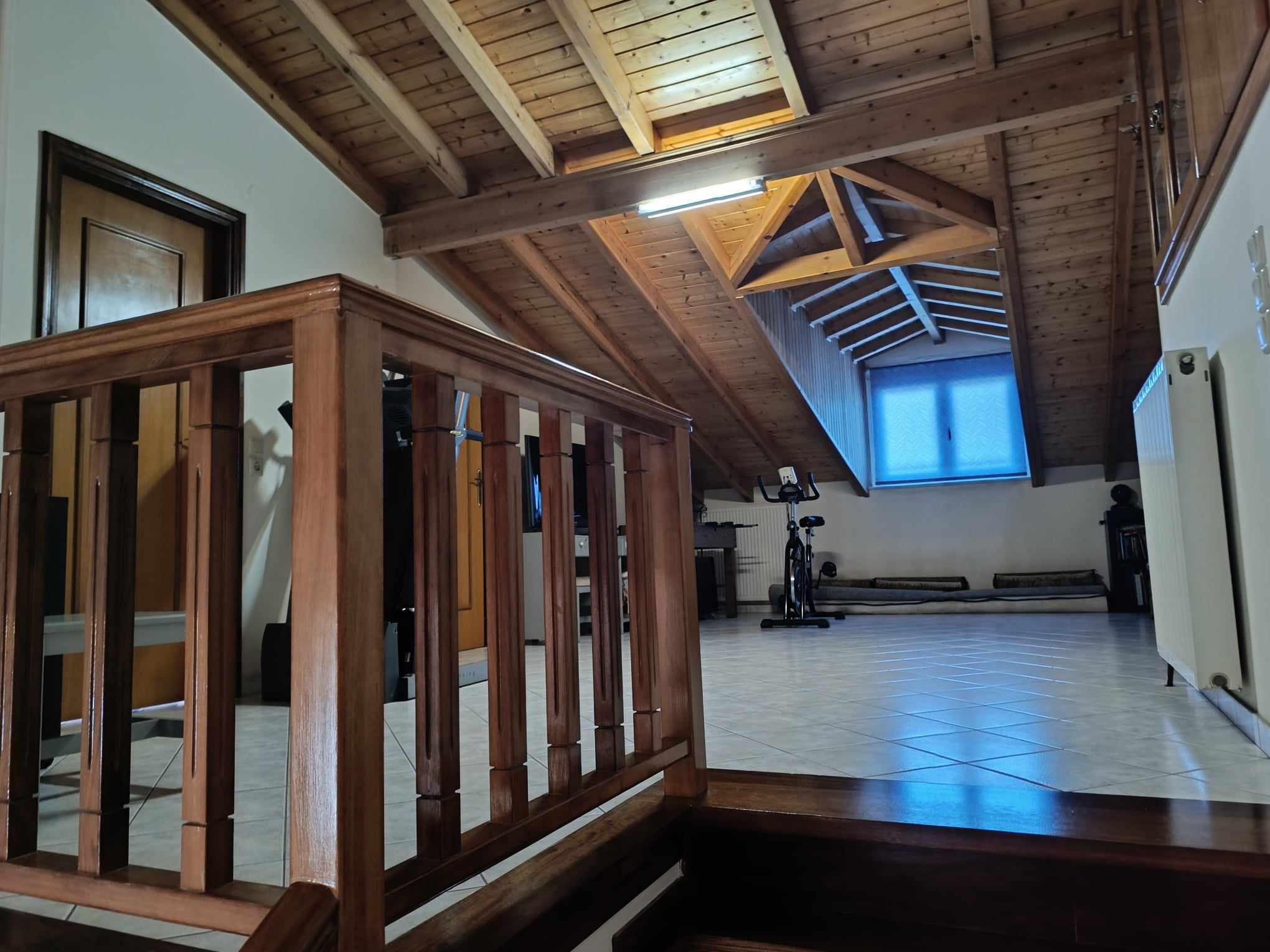 Sofita — attic lounge with exercise bike & beam ceiling