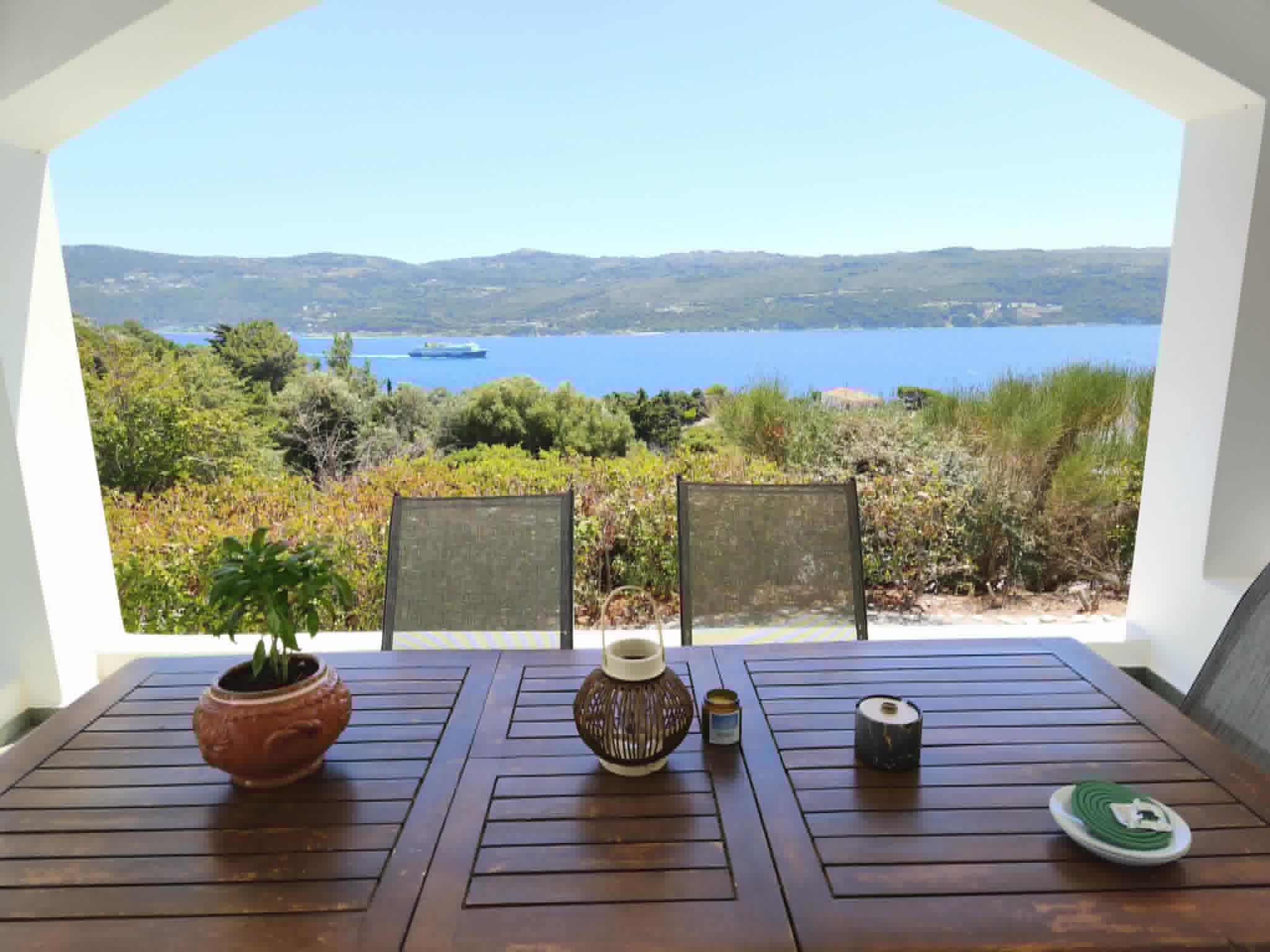 Terrace dining table framed by arches & sea view
