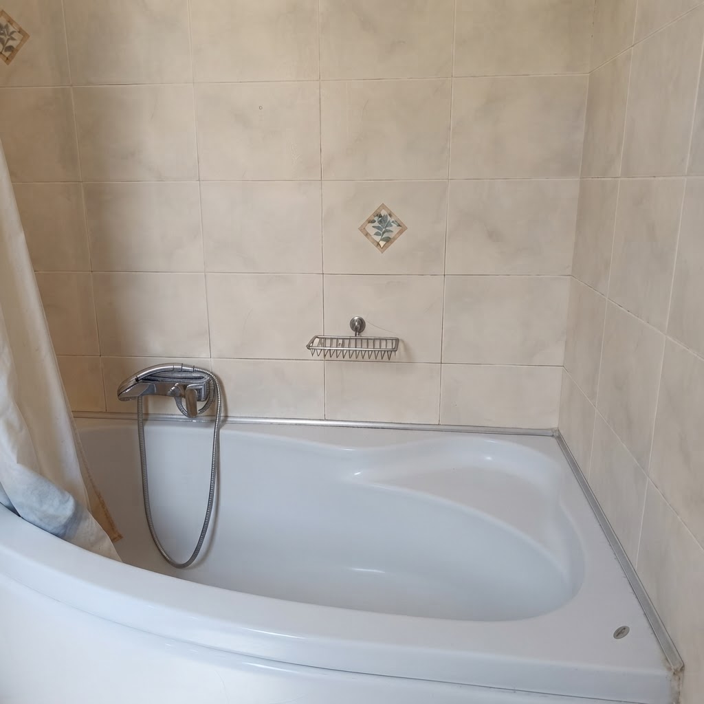 Bathroom with corner bathtub & marble-effect tiles
