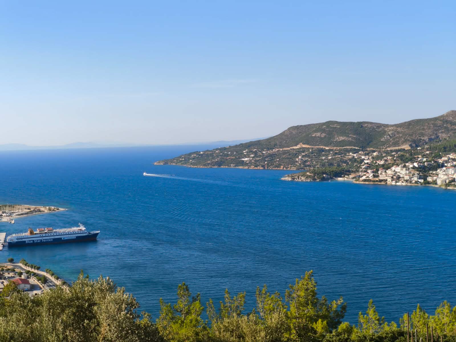 Ferry crossing the blue sea toward the headland