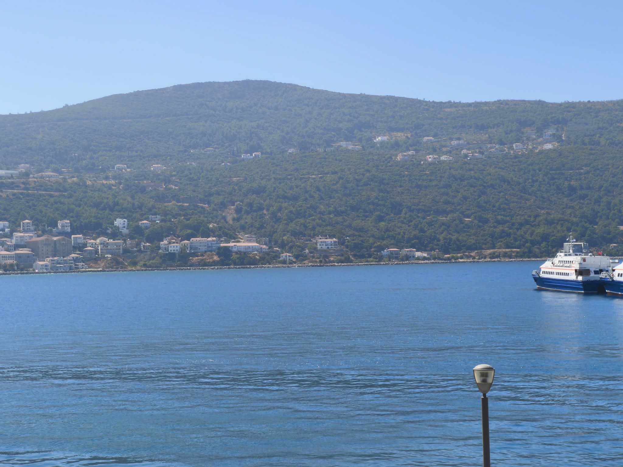 Bay, green mountain & ferry crossing the sea