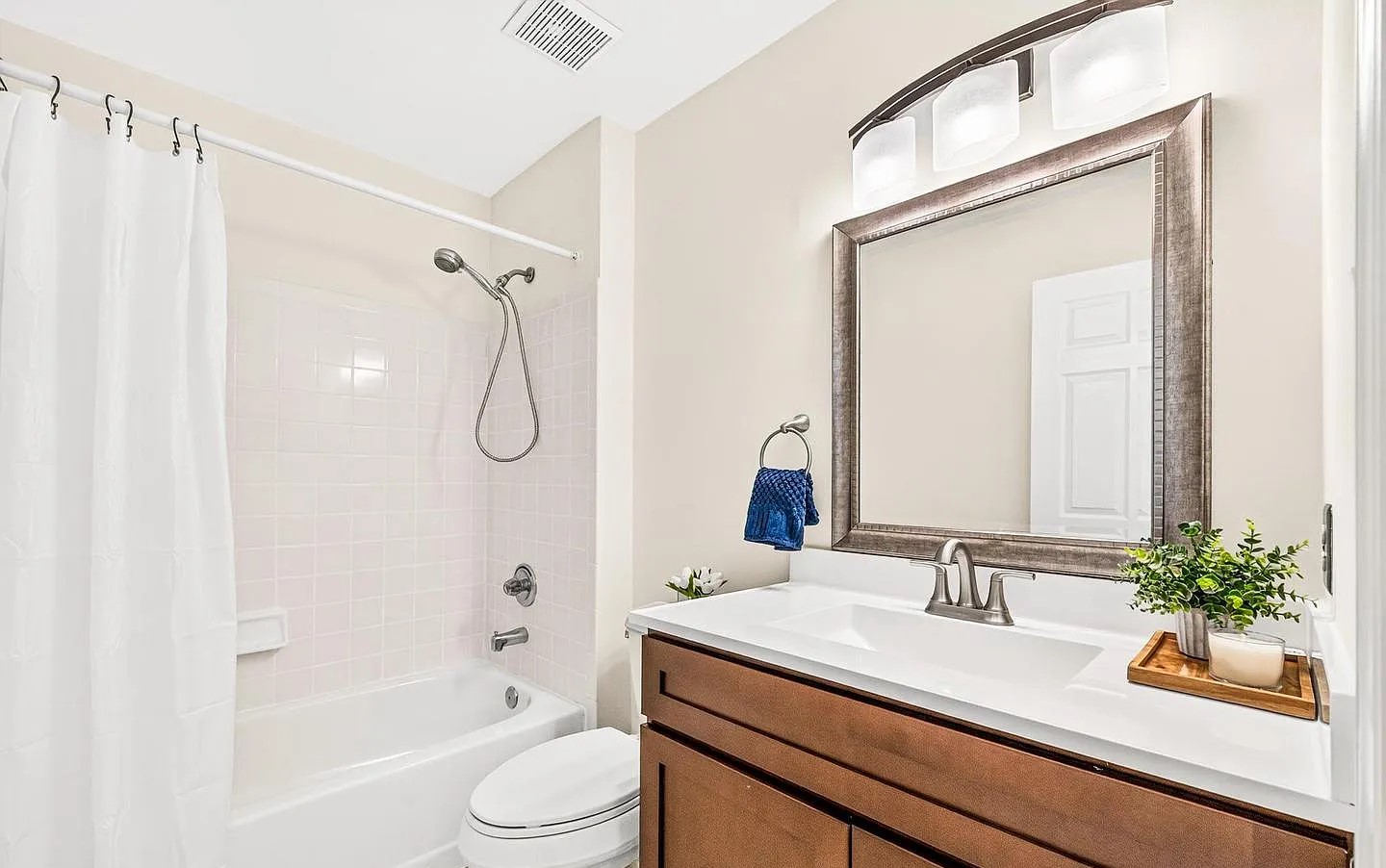 Wood vanity with tub-shower combo and blush square shower tile