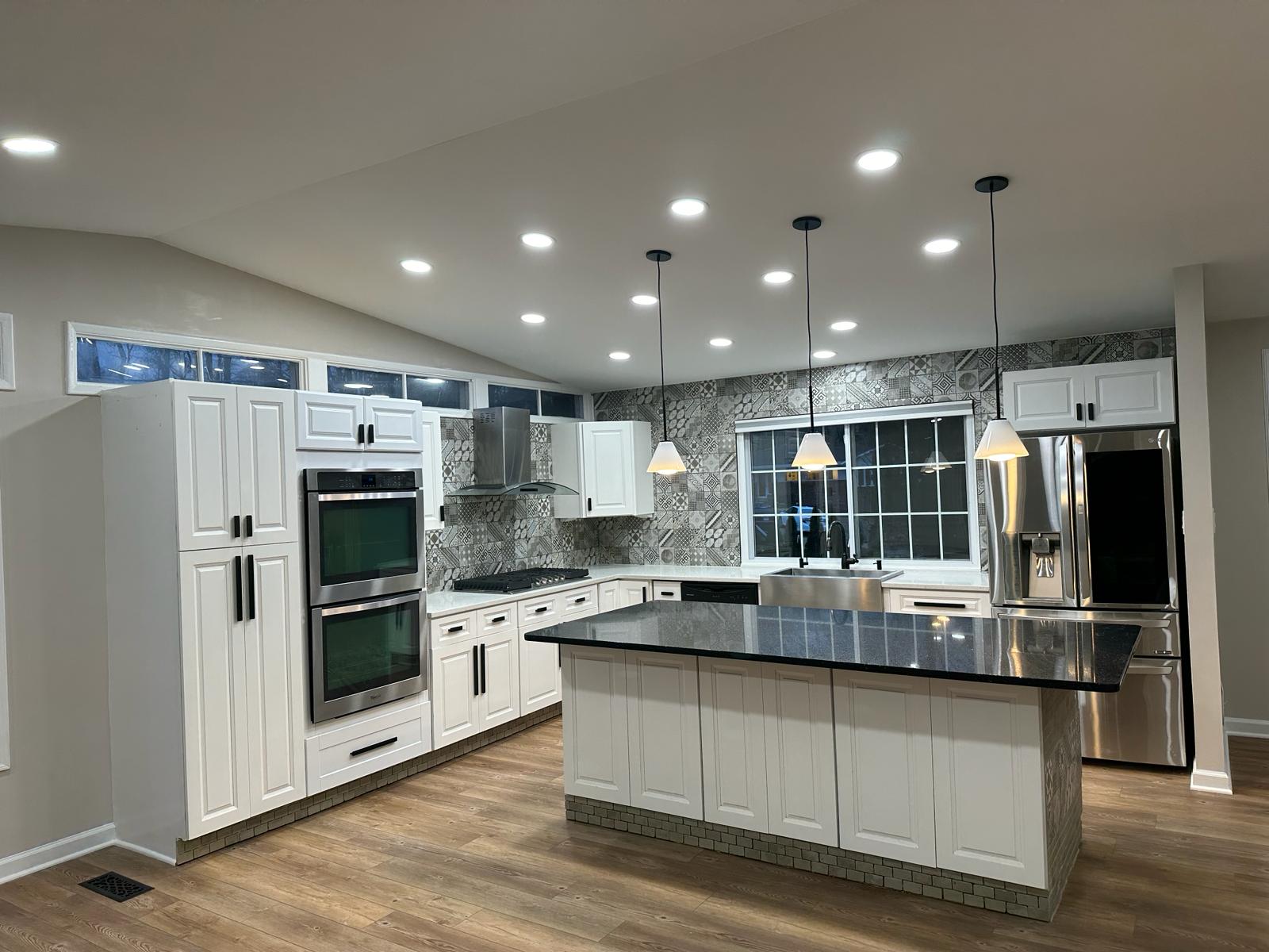 White shaker kitchen with black granite island, patterned backsplash and pendants