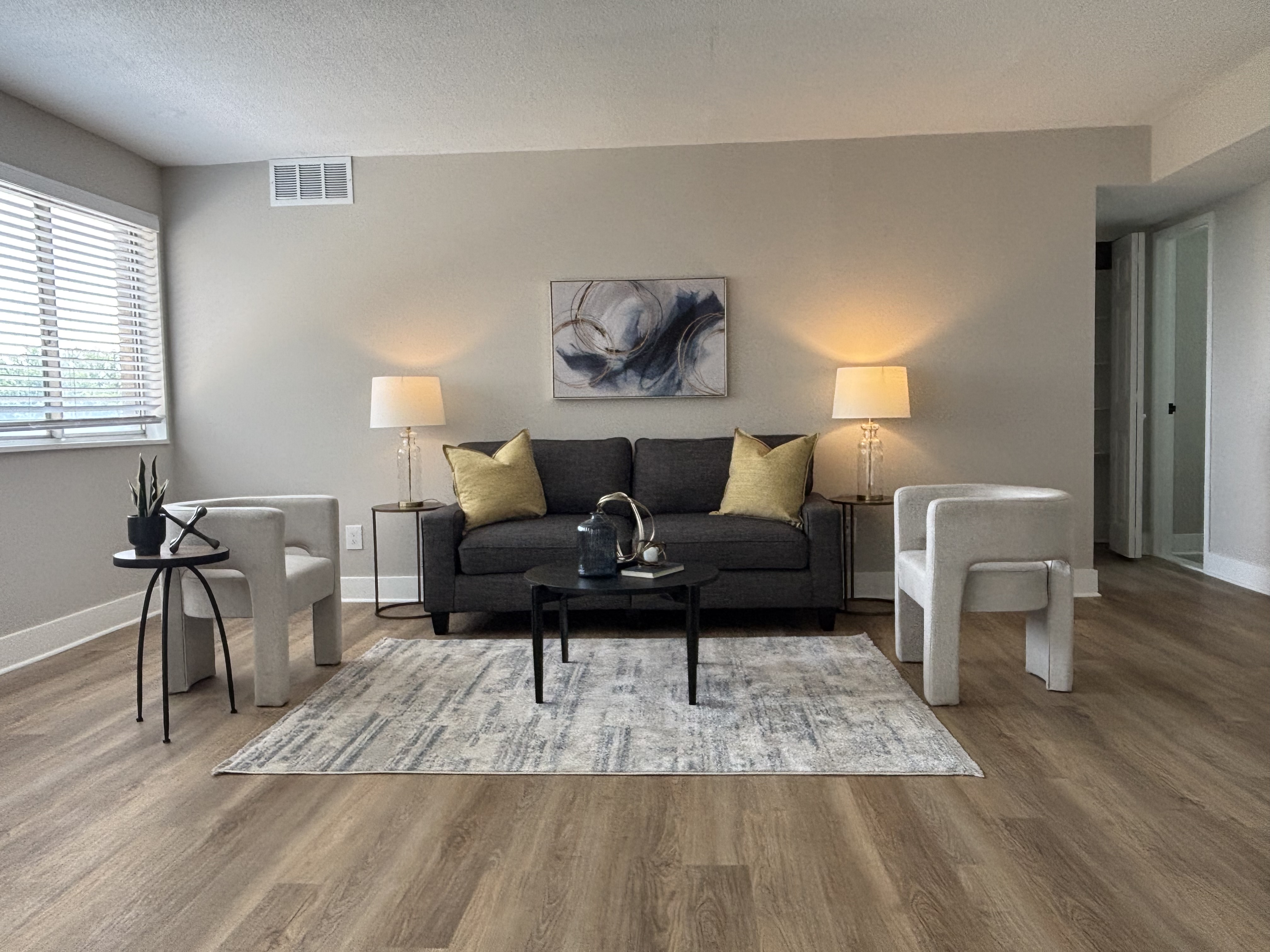Living room with wood-look plank flooring, charcoal sofa and abstract art