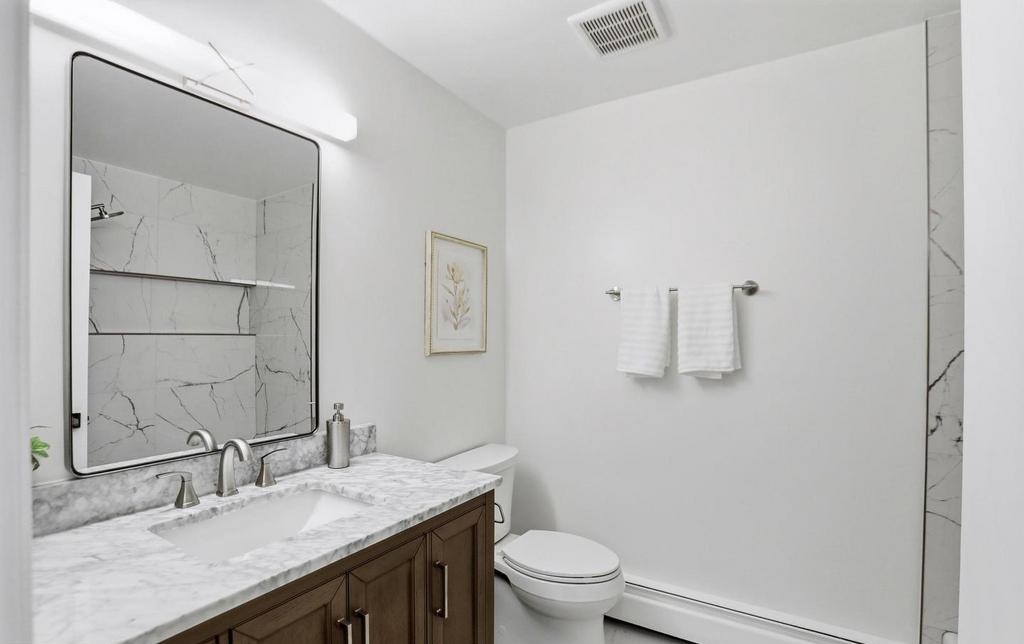 Dark wood vanity with marble counter, framed mirror and botanical art