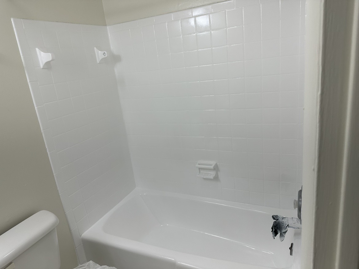 Freshly reglazed white bathtub with glossy tiled surround
