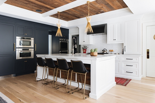 Two-tone kitchen with dark and white cabinets, wood-slat ceiling and brass pendants