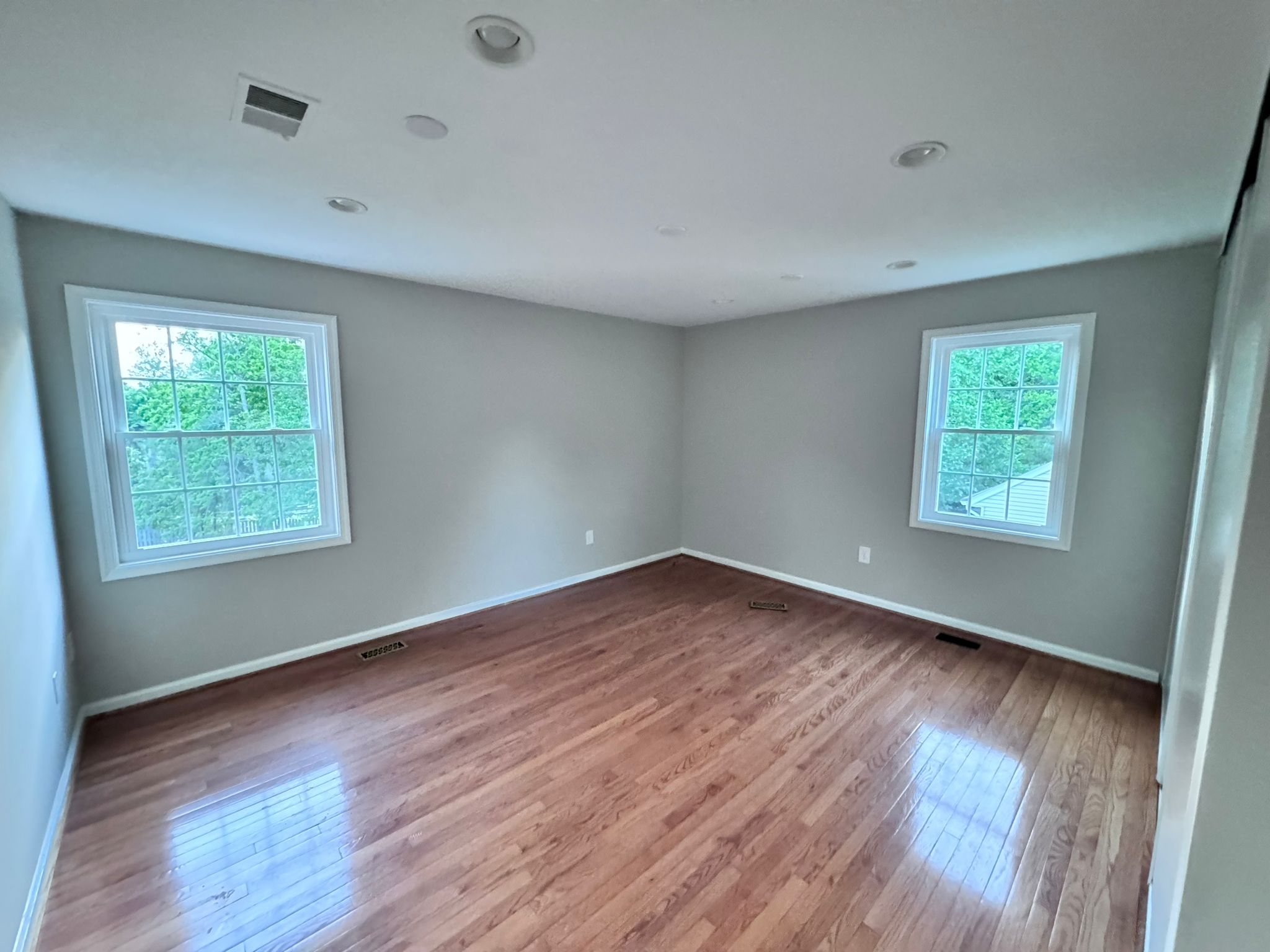 Finished room with reddish-brown hardwood floors and light grey walls