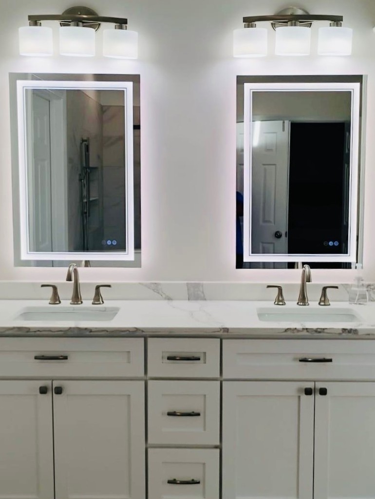 Double vanity with LED-backlit mirrors and three-light fixtures