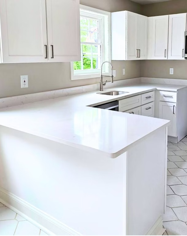 White shaker kitchen with slab quartz backsplash and hex tile floor