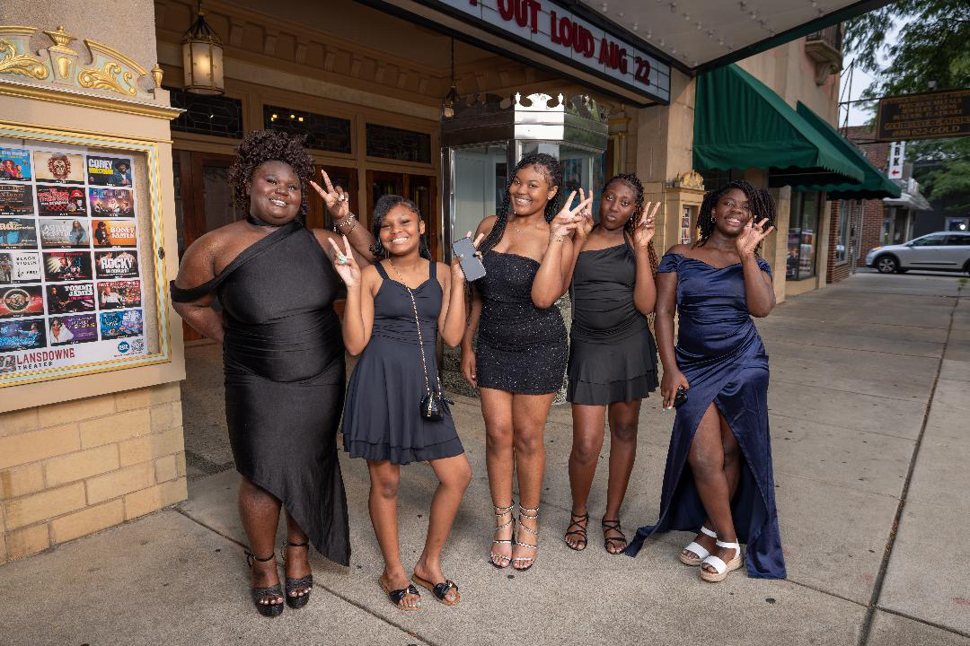 Five young women in formal dresses outside the Lansdowne Theater