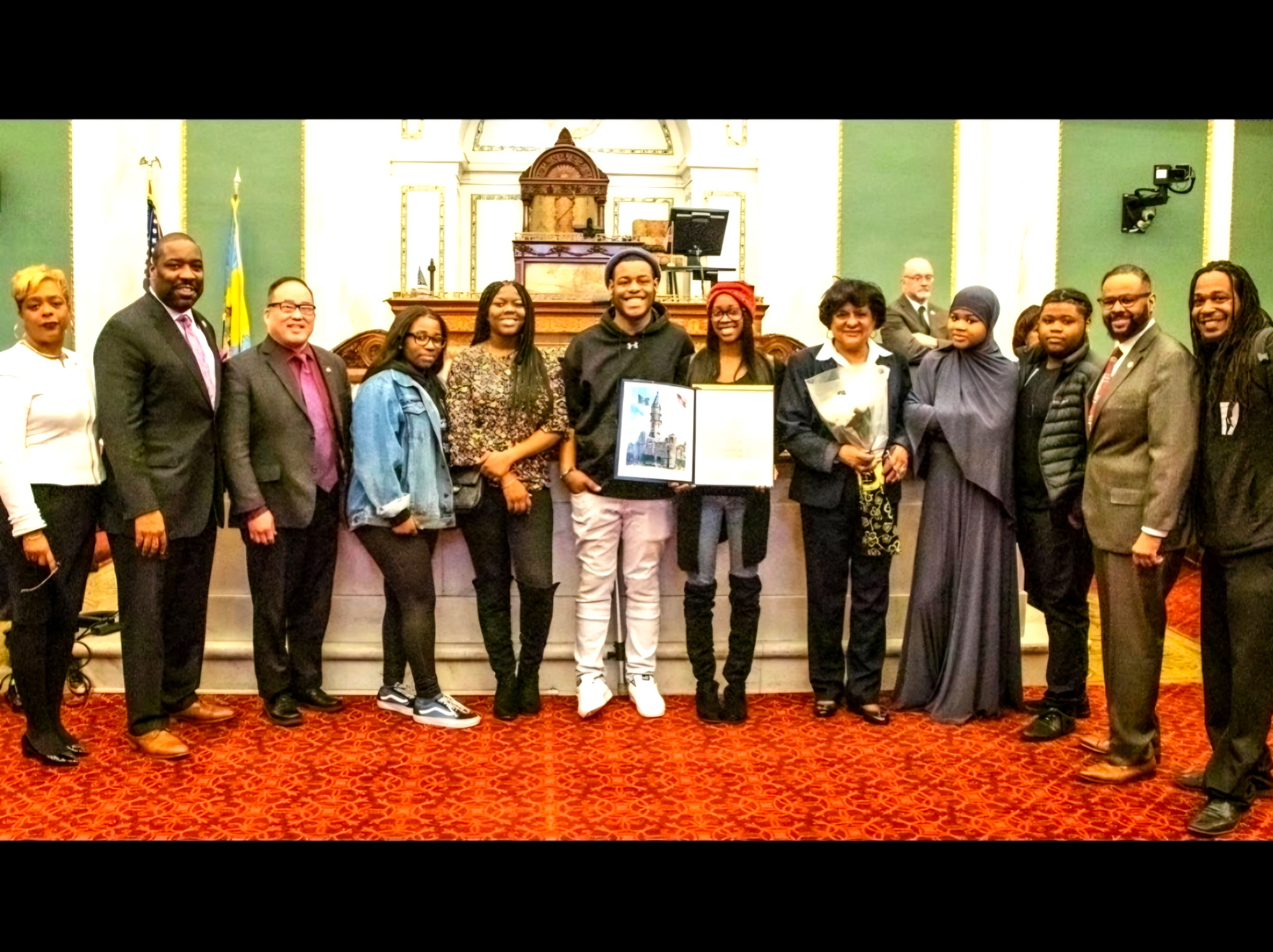 Alliance of the Living students standing with Philadelphia city officials in City Council chambers, holding the resolution