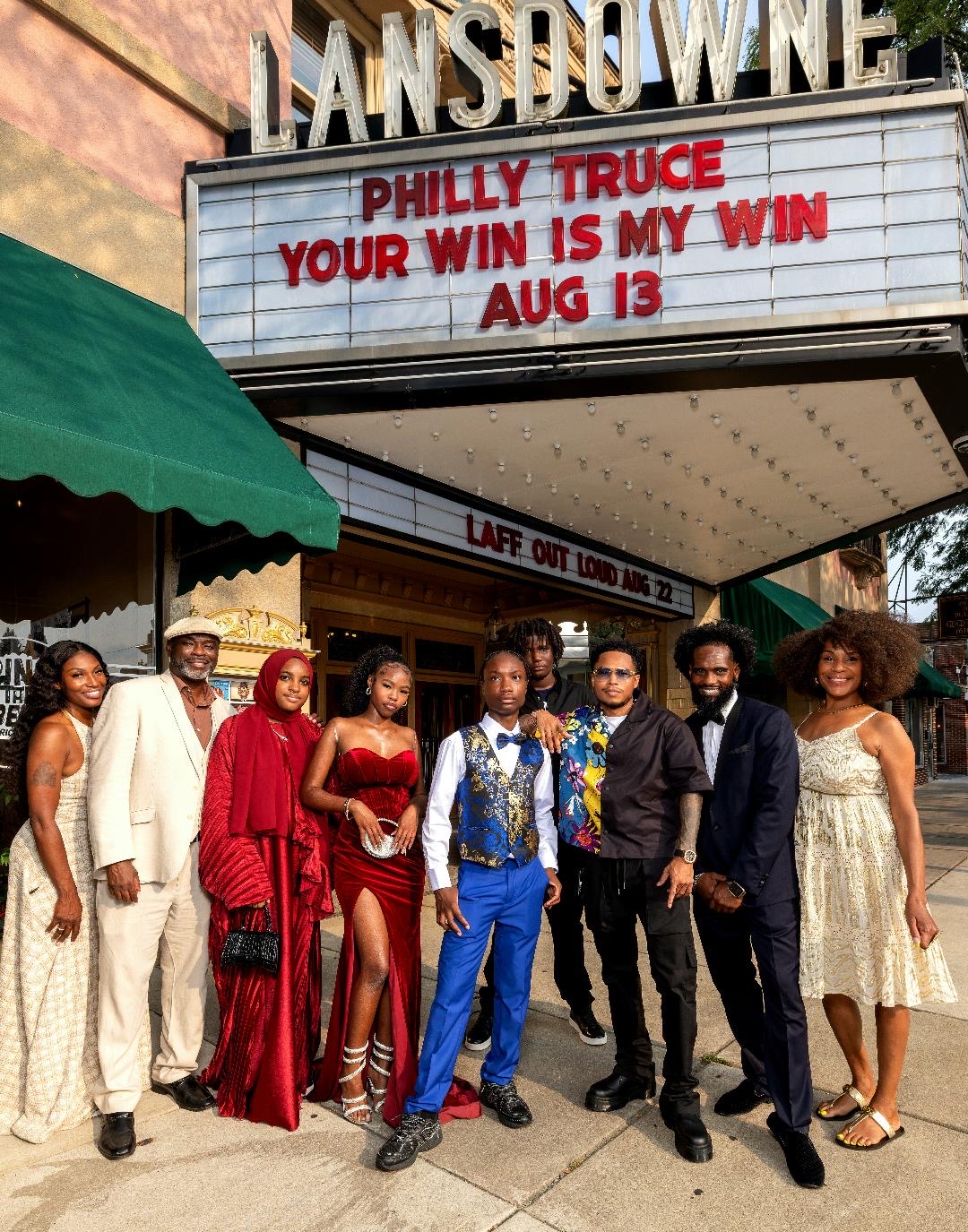 Cohort, families, and facilitators in formal attire beneath the Lansdowne Theater marquee