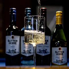 White wine being poured behind bottles of Sutter Home wine