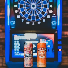 BullShooter electronic dartboard glowing beside cans of Smirnoff Ice