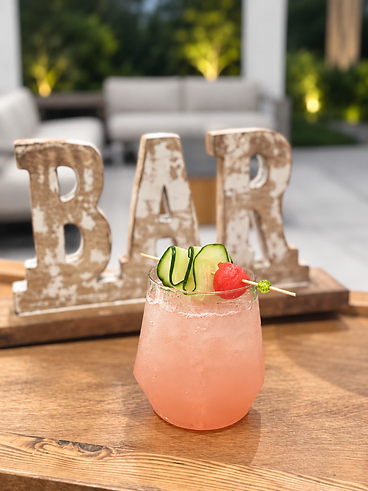 Blush cocktail served beside wooden BAR letters