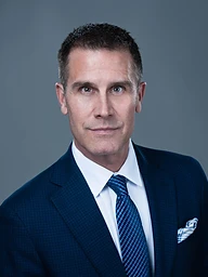 Bruno P. Allaire, suit and tie, studio portrait against a slate backdrop