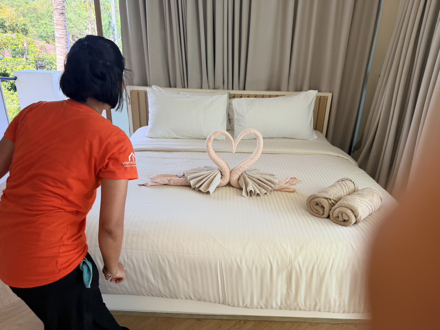 Crew member arranging towels into a heart on a freshly made bed
