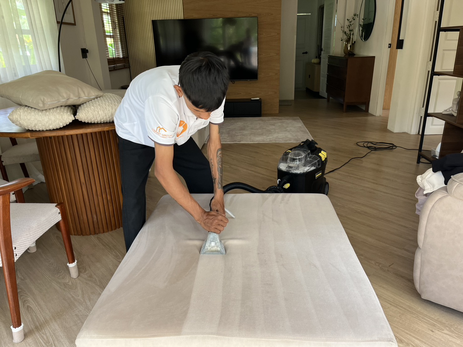 Crew member deep cleaning an upholstered ottoman with an extraction machine