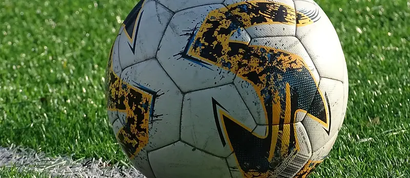 Bola de futebol em relvado sintético, junto à linha de campo