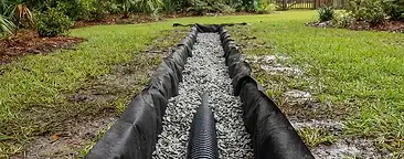 Newly installed French drain trench with gravel and perforated pipe in a residential backyard in the South Carolina Lowcountry