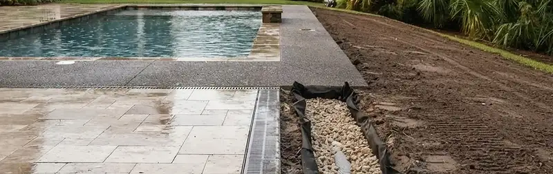 Residential backyard pool with stone decking beside a freshly graded drainage trench in the South Carolina Lowcountry