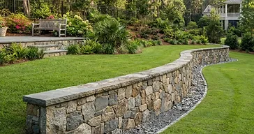 Finished stone retaining wall with proper drainage in a southern Lowcountry backyard, managing a slope with lush green lawn