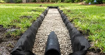 Newly installed French drain trench filled with clean gravel and a perforated pipe in a southern Lowcountry yard