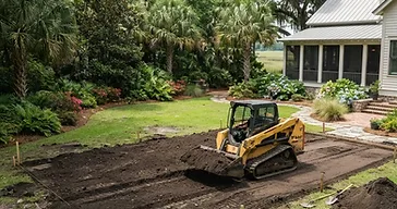 Professional yard grading with a skid steer moving soil in a southern Lowcountry residential yard