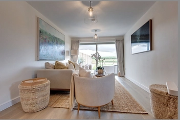 Bright living room with a cream sofa, art, and glass doors opening to the terrace