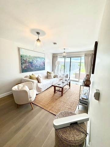 Living room with a slipcovered sofa, jute rug and abstract art above
