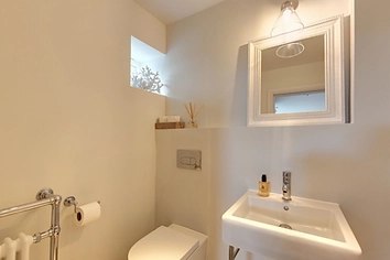 Compact cloakroom with wall-mounted sink, framed mirror and chrome radiator