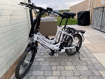 Two white folding electric bicycles parked on the patio beside the garden