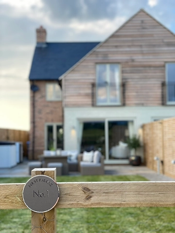 Circular guest parking plaque reading No.1 with the house behind