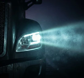 Truck headlight cutting through fog at night