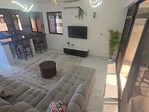 Living room — open-plan lounge with air-conditioning unit above the TV