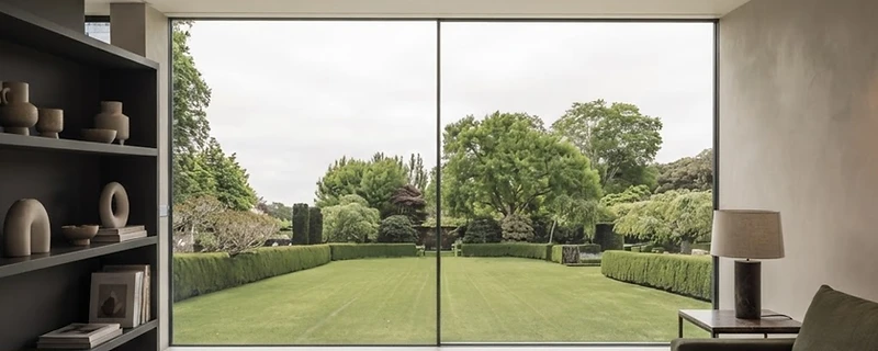 Large glass sliding panels in a slim aluminium frame at dusk