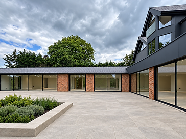 Modern courtyard house with continuous floor-to-ceiling glass sliding doors in black frames alternating with red brick pillars, anthracite cladding above