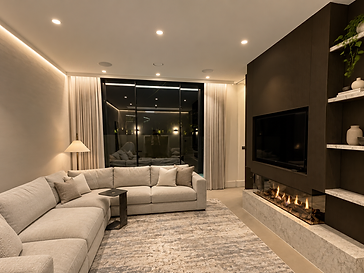 Contemporary living room at night with a dark media wall, linear gas fireplace and full-height black-framed sliding glass doors opening onto a dark patio