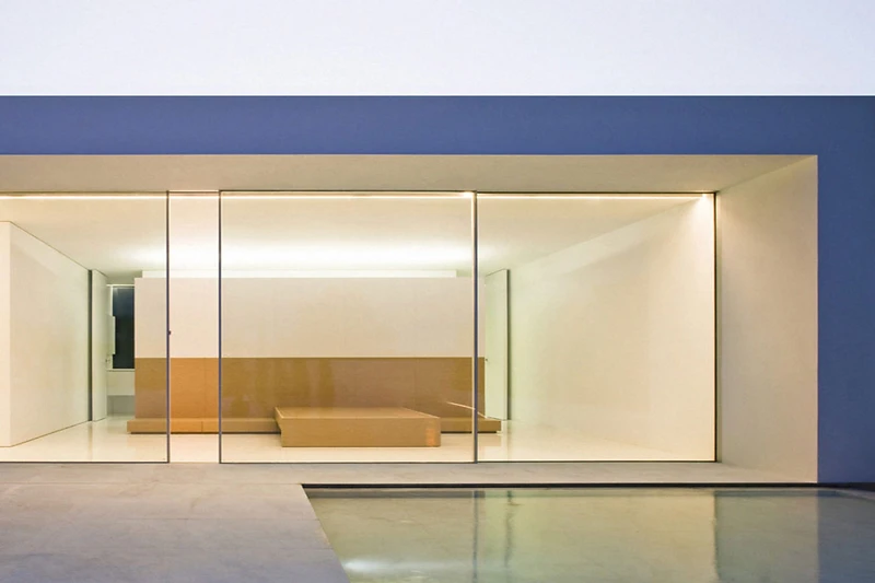 Minimal-frame sliding glass doors opening onto a garden at dusk