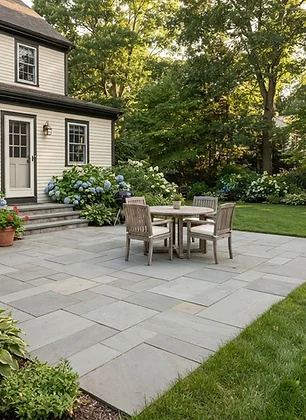 Natural gray stone patio with outdoor dining furniture and landscaped garden beds