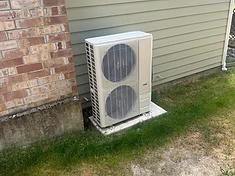 Outdoor condenser set on a fresh pad against sage siding