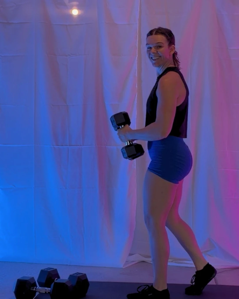 Coach Samantha curling a dumbbell during a guided at-home workout