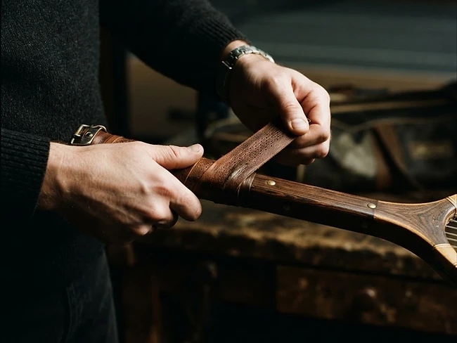Hands tightening a leather racket grip