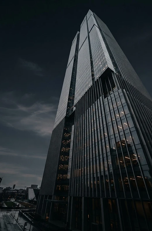 A modern glass tower rising into the evening sky