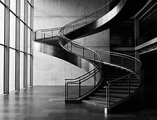 A sweeping modern staircase lit by tall windows